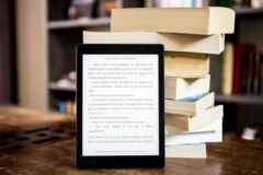 E-Book-Reader lehnt an einem Bücherstapel