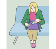 Eine Frau sitzt auf einem Sofa und schaut in ihre Tasche