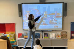 Eine Frau zeigt Kindern etwas am Smartboard
