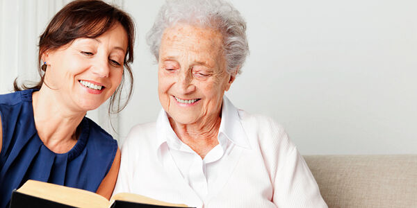 Junge Frau liest älterer Dame vor