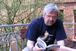 Schriftsteller Alexander Häusser liest auf einem Balkon in einem Buch