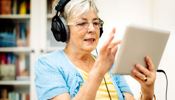 Seniorin mit Kopfhörern und Tablet-PC